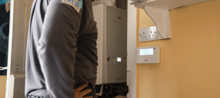 Technician working inside utility room on heating system