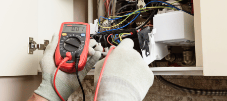 Electrician testing heating controls and wiring setup